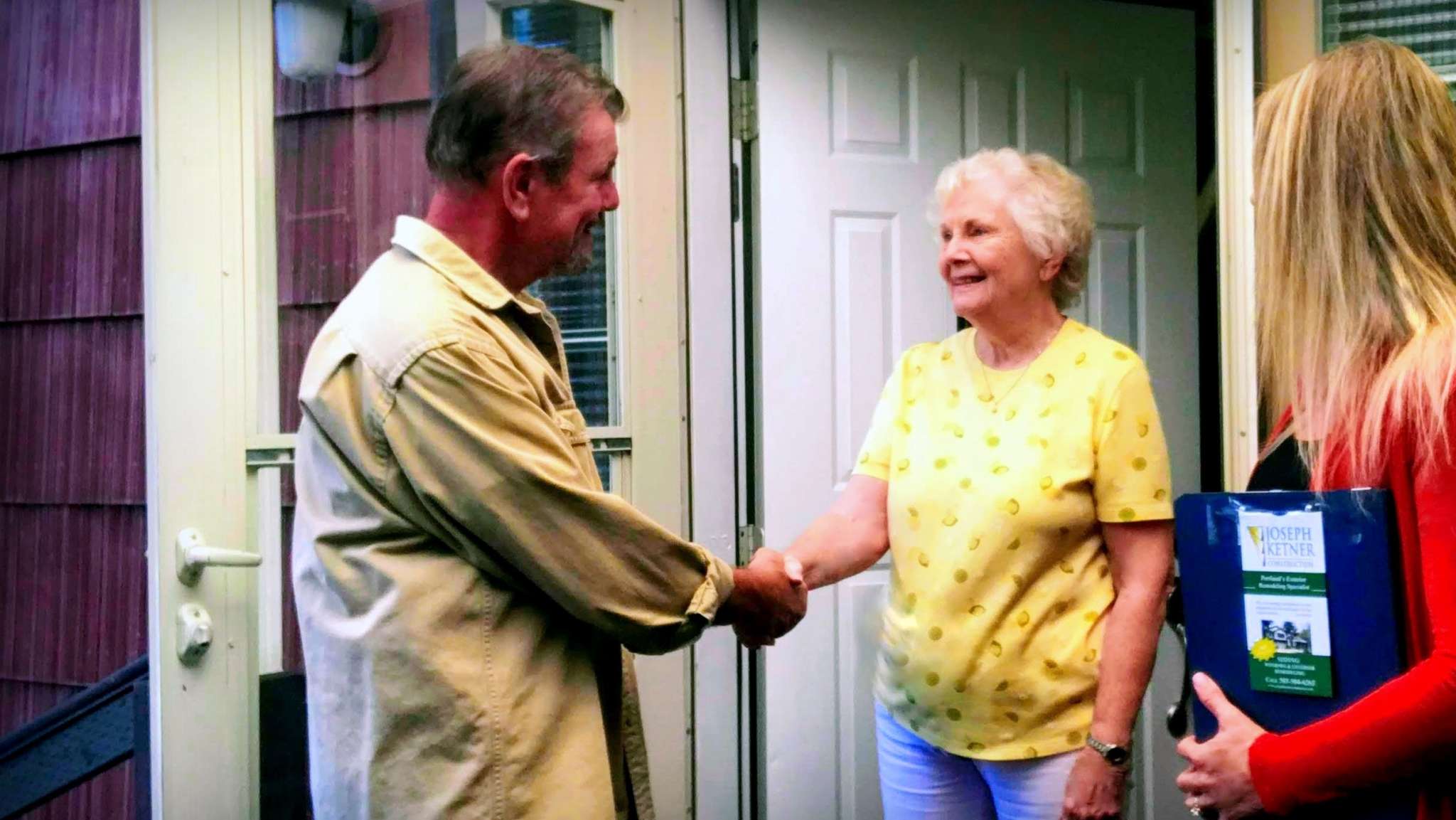Two people shaking hands at the front door of a home